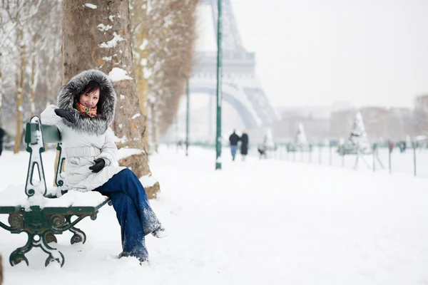 Beautiful girl in fur hood sitting on a bench near the Eiffel to — Stock Photo, Image