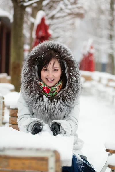 Menina bonita em capuz de pele brincando com neve — Fotografia de Stock