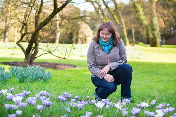 Girl watching at first spring crocuses in a park — Stock Photo, Image