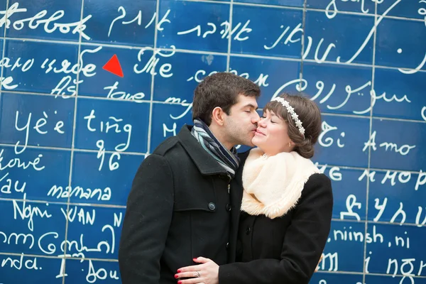 Couple kissing across the I Love You wall in Paris — Stock Photo, Image