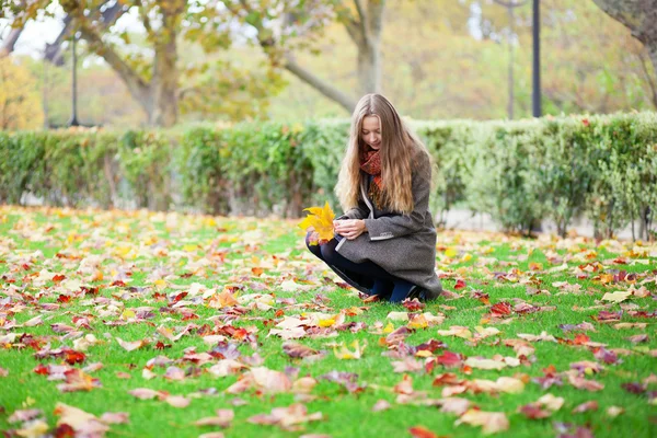 Girl with long hair gathering autumn leaves — Stock Photo, Image