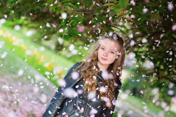 Ragazza sotto la caduta petali rosa in un giorno di primavera — Foto Stock