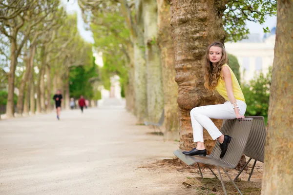 Dívka sedící na lavičce v parku — Stock fotografie
