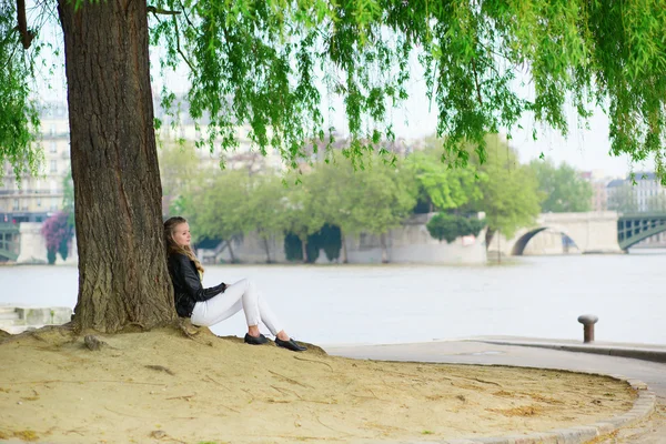 Chica leyendo bajo un árbol cerca del Sena — Foto de Stock