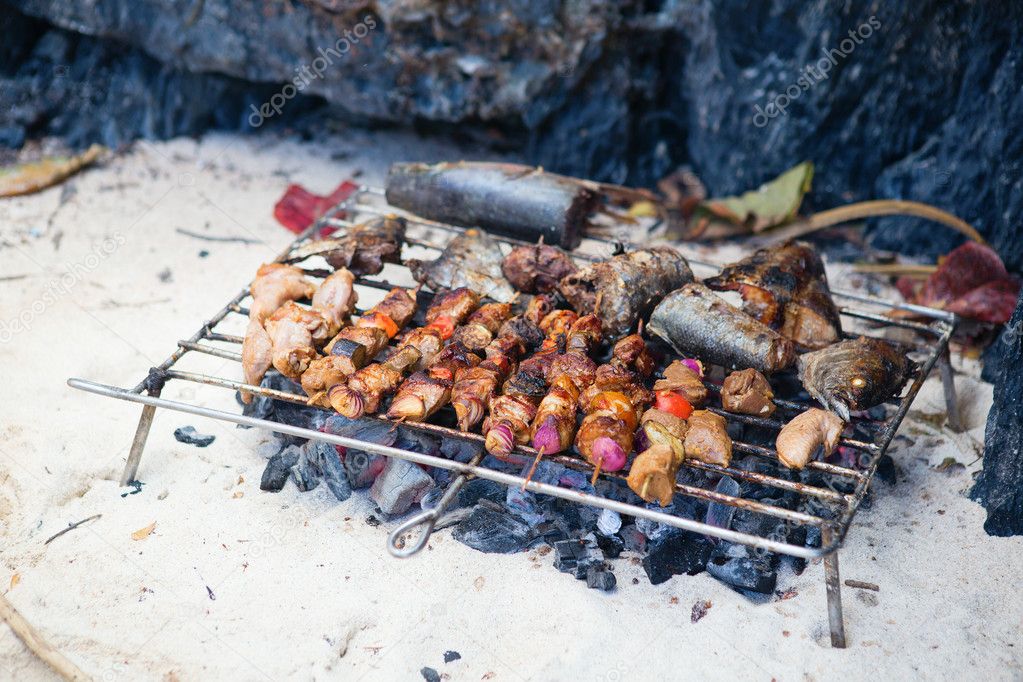 Meet and fresh fish grilled on a beach