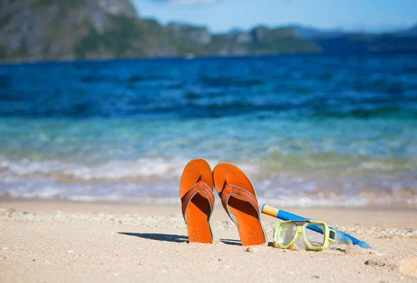 Pantofle, maska a šnorchl na písčité pláži — Stock fotografie
