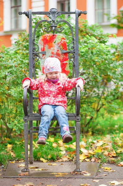Legrační malá holka sedí na židli ozdobný — Stock fotografie