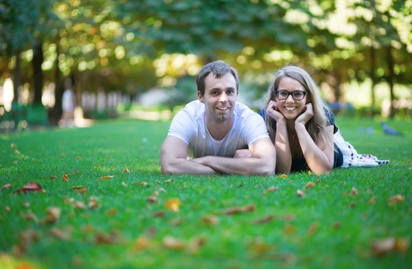 Feliz pareja sonriente tendida en la hierba —  Fotos de Stock