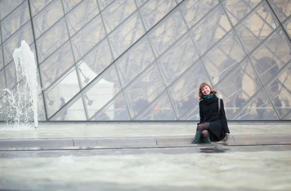 Smějící se dívka sedící poblíž pyramida v Louvru — Stock fotografie