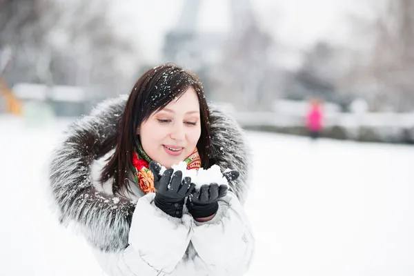 Beautiful girl blowing on snow in her hands — Stock Photo, Image