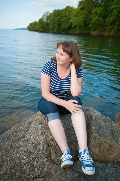 Dziewczyna siedzi w pobliżu jeziora — Zdjęcie stockowe
