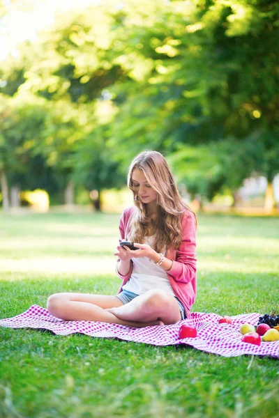 Meisje met behulp van haar mobiele telefoon buiten — Stockfoto