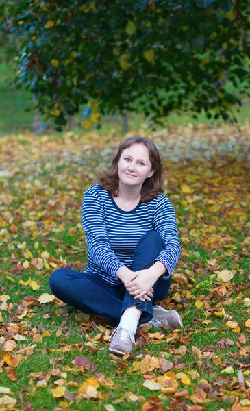 Meisje, zittend op de grond op een daling dag — Stockfoto