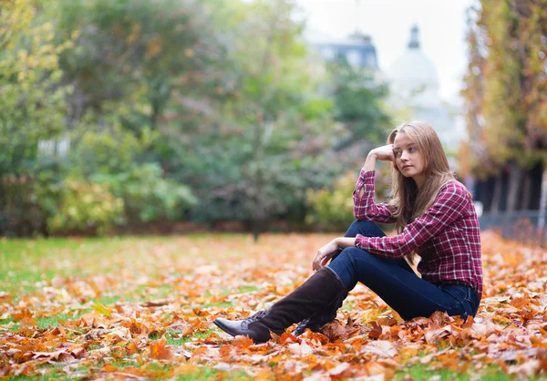 Thoughtful girl sitting on the ground at fall — Stock Photo, Image