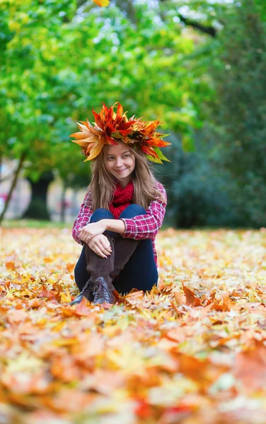 Κορίτσι στο Φθινοπωρινό στεφάνι που κάθεται στο έδαφος — Φωτογραφία Αρχείου