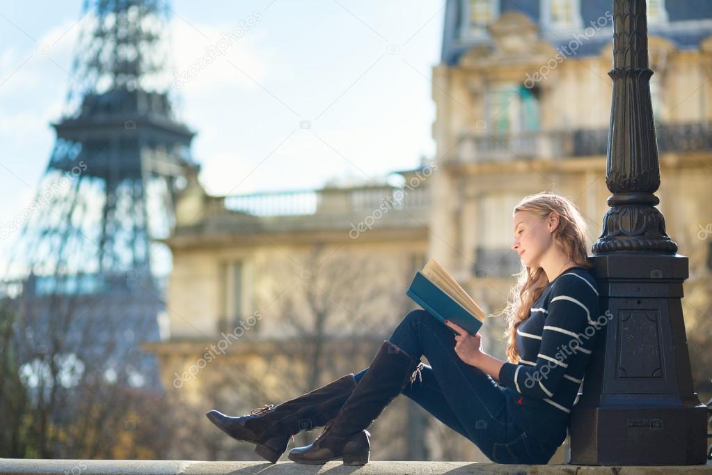 Beautiful young woman in Paris, reading a book