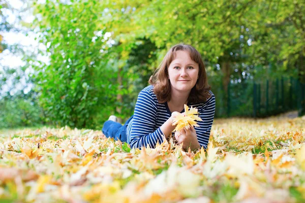 Meisje liggend op de grond bedekt met vallen bladeren — Stockfoto