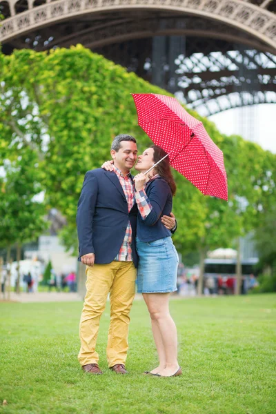 Couple under red umbrella near the Eiffel tower — Stock Photo, Image