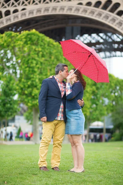 Couple under red umbrella near the Eiffel tower — Stock Photo, Image