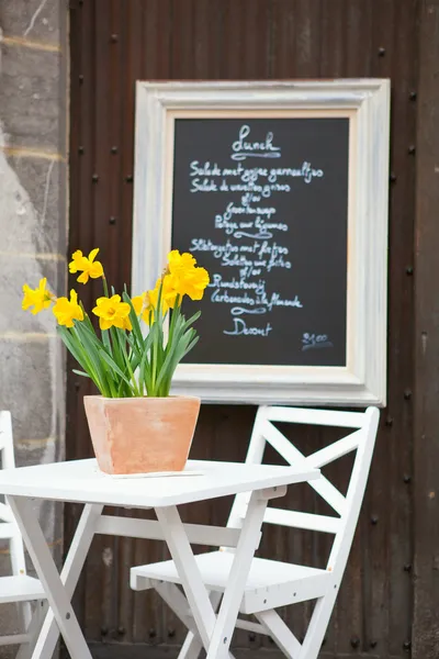 Mesa de um café de rua com jonquils amarelos — Fotografia de Stock