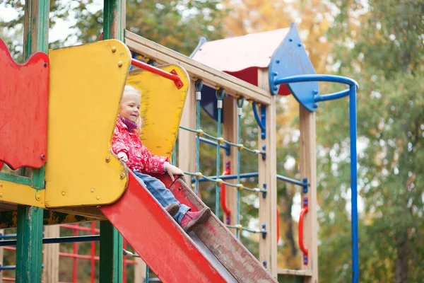 Little girl preparing to slither from a slide — Stock Photo, Image