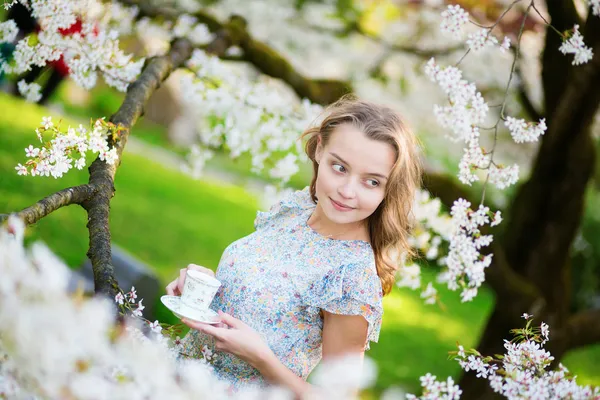 Beautiful woman in cherry garden with cup of tea — Stock Photo, Image