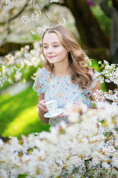 Mulher bonita no jardim de cereja com xícara de chá — Fotografia de Stock