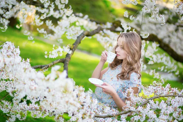 Mulher bonita no jardim de cereja com xícara de chá — Fotografia de Stock