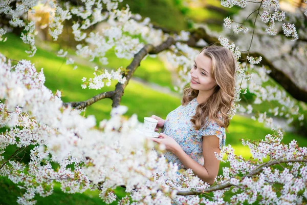 Krásná žena pít čaj v třešňové zahrady — Stock fotografie