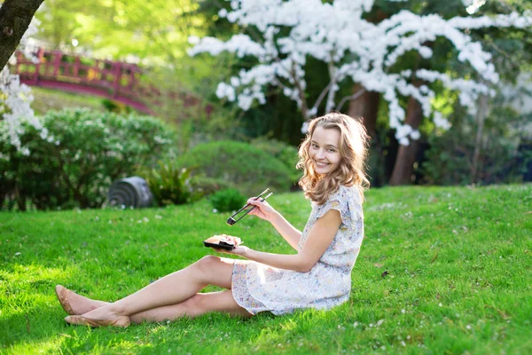 Young woman eating sushi in Japanese park — Stock Photo, Image