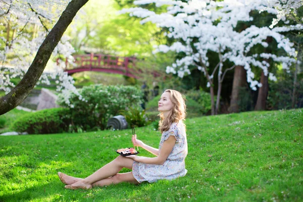 Jeune femme mangeant des sushis dans le parc japonais — Photo