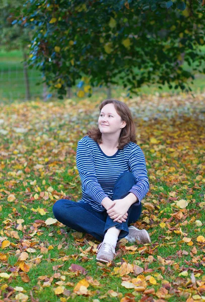 Flicka sitter på marken på en höst dag — Stockfoto