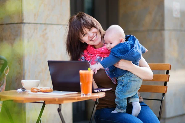 Ung mamma med lille son arbetar på sin laptop — ストック写真