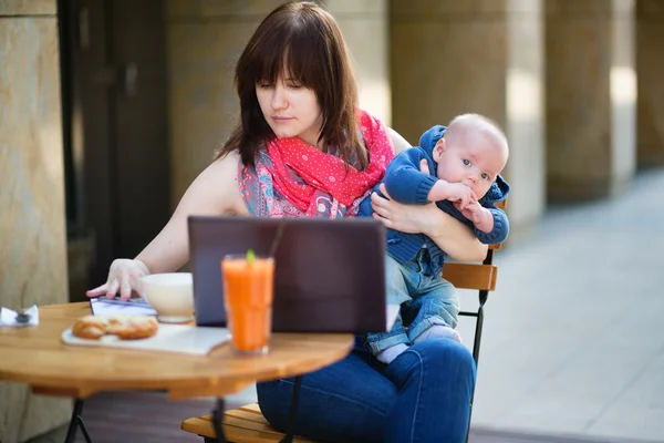 Ung mamma med lille son arbetar på sin laptop — Stockfoto