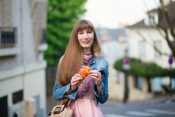 Menina com croissant em uma rua de Paris — Fotografia de Stock