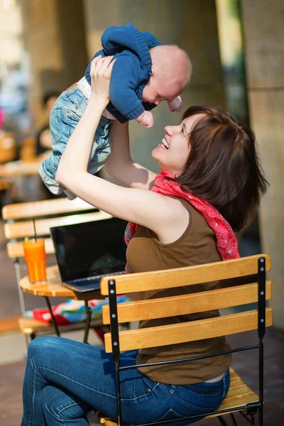 Glad ung mamma med sin lilla son i ett café — Stockfoto