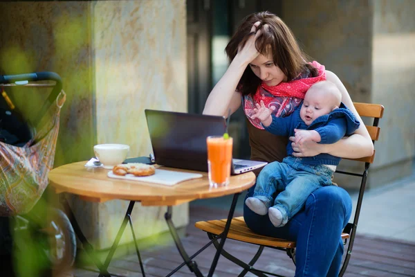 Tired young mother working oh her laptop — Stock Photo, Image