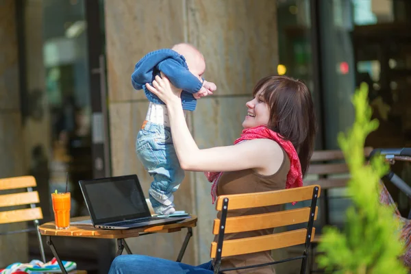 Glad ung mamma med sin lilla son i ett café — Stockfoto