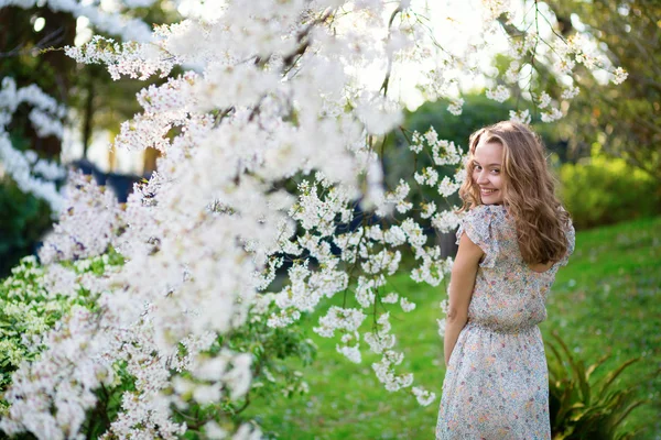 Ung kvinde i blomstrende kirsebærhave - Stock-foto