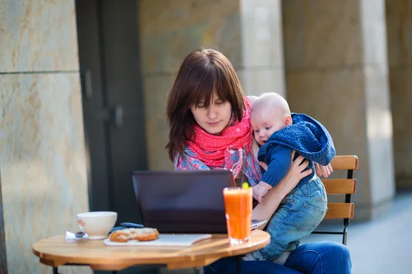 Молодая работающая мать с маленьким сыном в кафе — стоковое фото