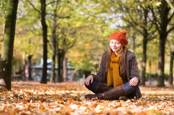 Mooi meisje, zittend op de grond op val — Stockfoto