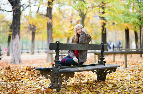 Jong meisje, zittend op een bankje in het park — Stockfoto