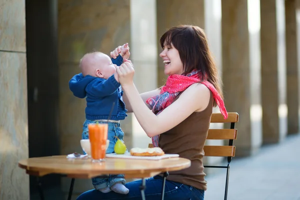 Glad ung mamma med barn i ett café — Stockfoto