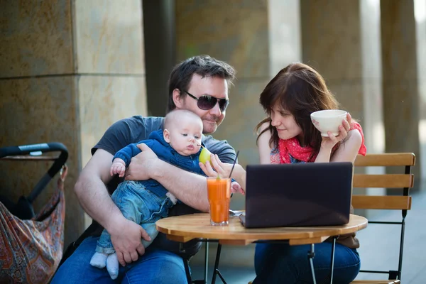 Familia feliz de tres en un café al aire libre —  Fotos de Stock