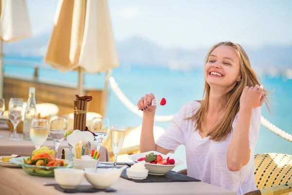 Mujer joven comiendo frutas en un restaurante de playa — Foto de Stock