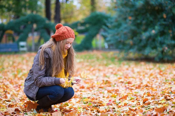 Chica reuniendo hojas en un día de otoño — Foto de Stock