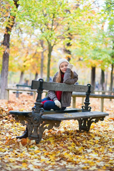 Sad girl sitting on a bench in park — Stock Photo, Image