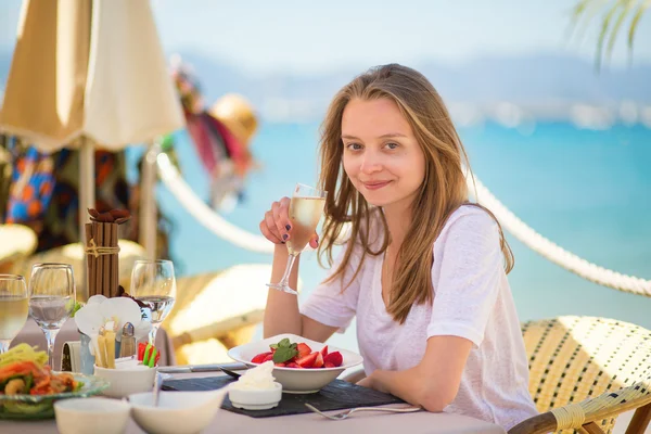 Młoda kobieta jedzenie owoców w restauracji na plaży — Zdjęcie stockowe