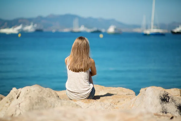 Молода дівчина сидить на березі моря — стокове фото