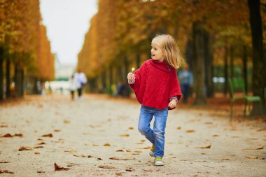 Paris 'te bir sonbahar günü Tuileries bahçesinde yürüyen sevimli anaokulu kızı. Mutlu çocuk sonbahar gününün tadını çıkarıyor. Fransa 'da sonbahar sezonu. Çocuklar için açık hava sonbahar aktiviteleri